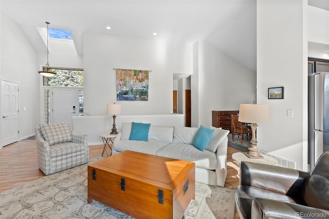 living room featuring light wood-type flooring, a skylight, high vaulted ceiling, and recessed lighting