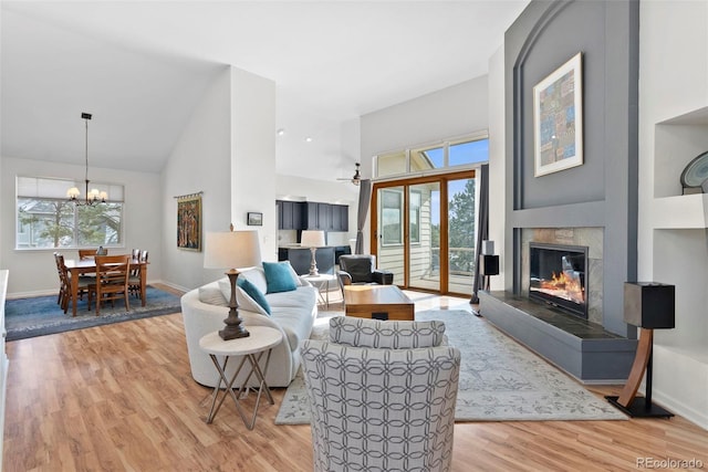 living room with light wood-style floors, baseboards, a fireplace, and high vaulted ceiling