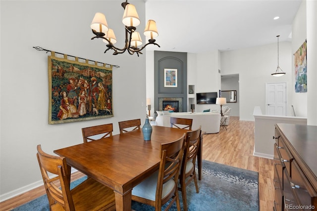 dining area featuring light wood-style flooring, a fireplace, baseboards, and recessed lighting