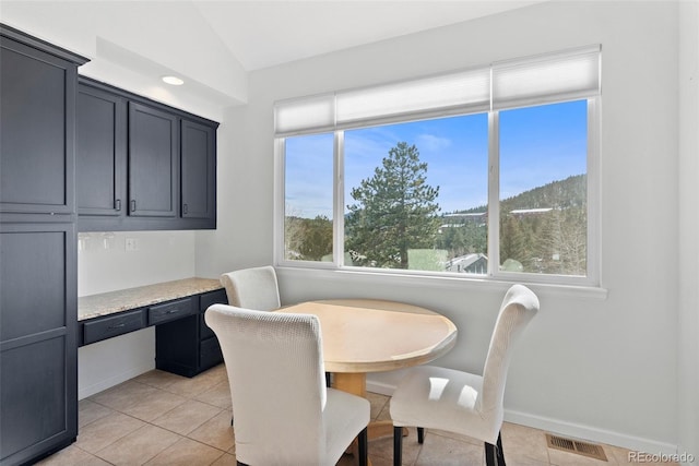 dining area with lofted ceiling, light tile patterned floors, visible vents, baseboards, and built in study area