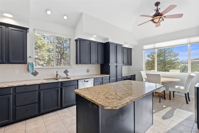 kitchen with lofted ceiling, a sink, backsplash, light stone countertops, and dishwasher