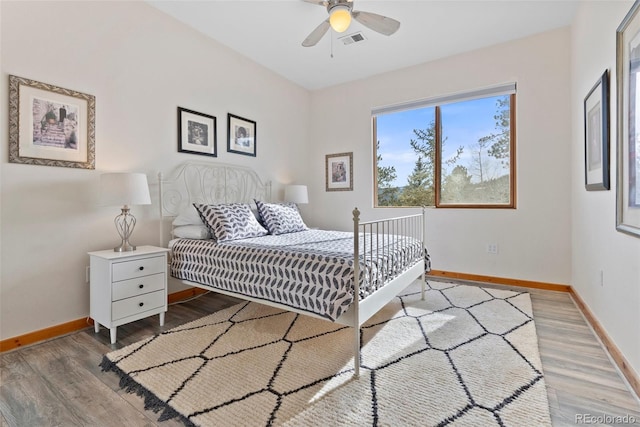 bedroom featuring visible vents, ceiling fan, baseboards, and wood finished floors