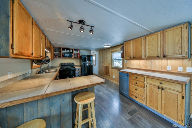 kitchen featuring sink, tile countertops, dark wood-type flooring, and black appliances