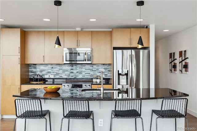 kitchen with a breakfast bar area, appliances with stainless steel finishes, tasteful backsplash, decorative light fixtures, and light brown cabinetry