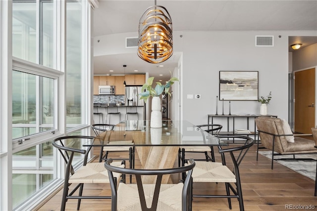 dining area with wood-type flooring and a notable chandelier