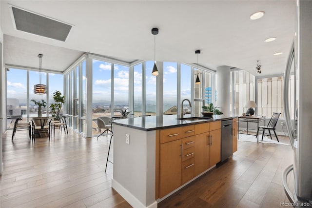 kitchen with decorative light fixtures, sink, expansive windows, and an island with sink