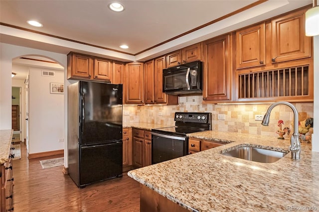 3131 E Alameda Ave Unit 704, Denver, CO 80209 - kitchen featuring black appliances, a sink, arched walkways, light stone countertops, and wood finished floors