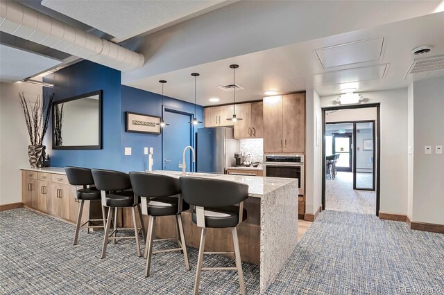 3131 E Alameda Ave Unit 704, Denver, CO 80209 - kitchen featuring stainless steel appliances, light carpet, baseboards, and a breakfast bar