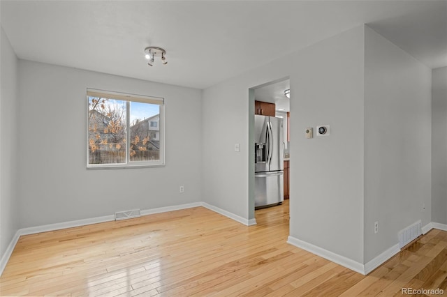 spare room featuring visible vents, baseboards, and light wood-style flooring