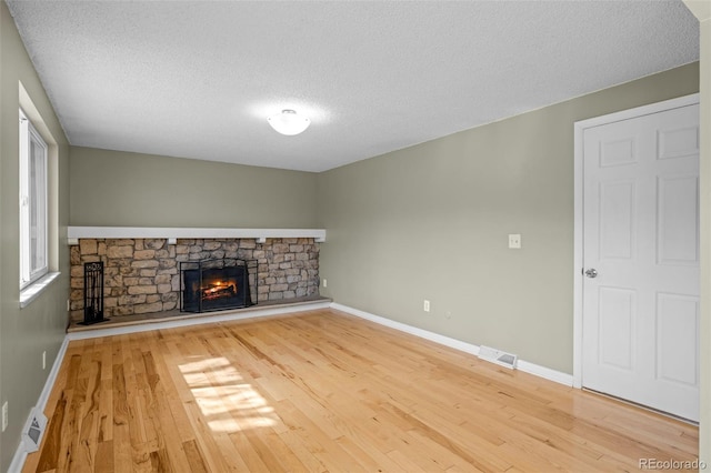 unfurnished living room featuring visible vents, a fireplace, baseboards, and light wood-style floors