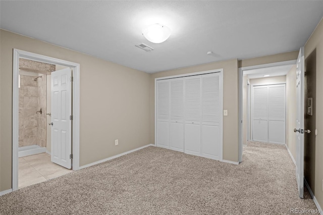 unfurnished bedroom featuring visible vents, light carpet, ensuite bathroom, a closet, and baseboards