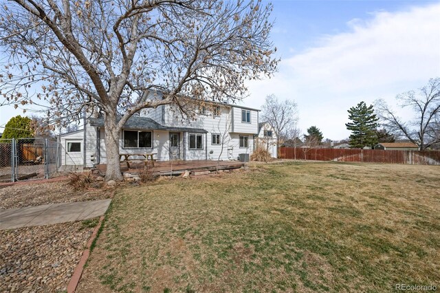 back of house featuring a lawn, a wooden deck, and fence