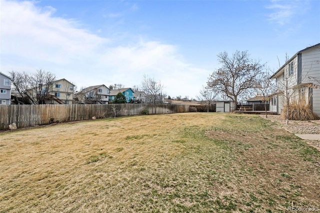 view of yard with a storage unit, a residential view, an outdoor structure, and a fenced backyard