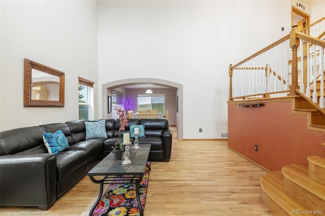 11960 Conestoga Trl, Elbert, CO 80106 - living room with arched walkways, light wood-style flooring, a towering ceiling, and stairway