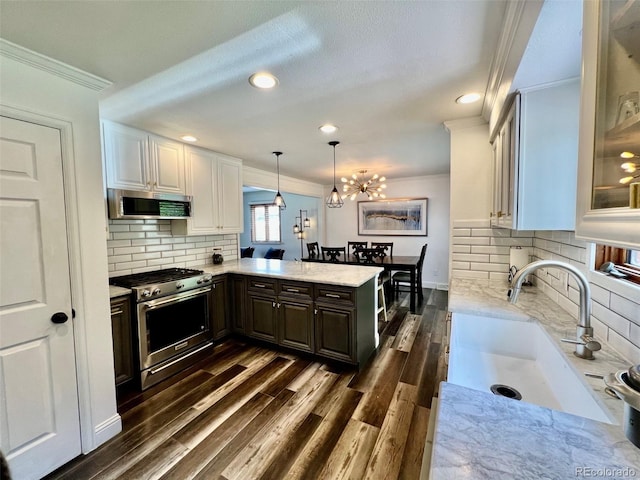 kitchen featuring crown molding, a sink, stainless steel appliances, a peninsula, and decorative backsplash