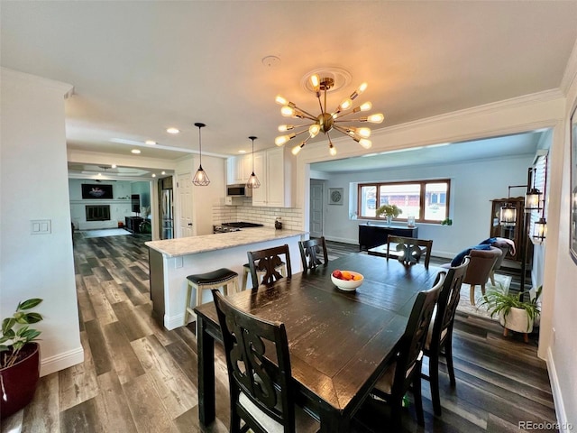 dining room featuring a chandelier, recessed lighting, baseboards, dark wood-type flooring, and ornamental molding