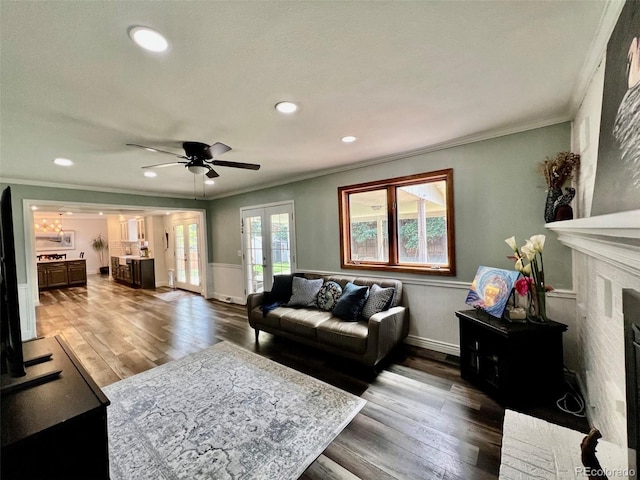 living area featuring crown molding, wainscoting, and wood finished floors