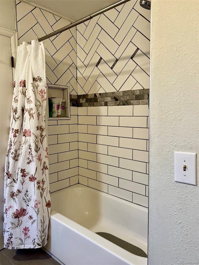 bathroom featuring a textured wall and shower / bath combo