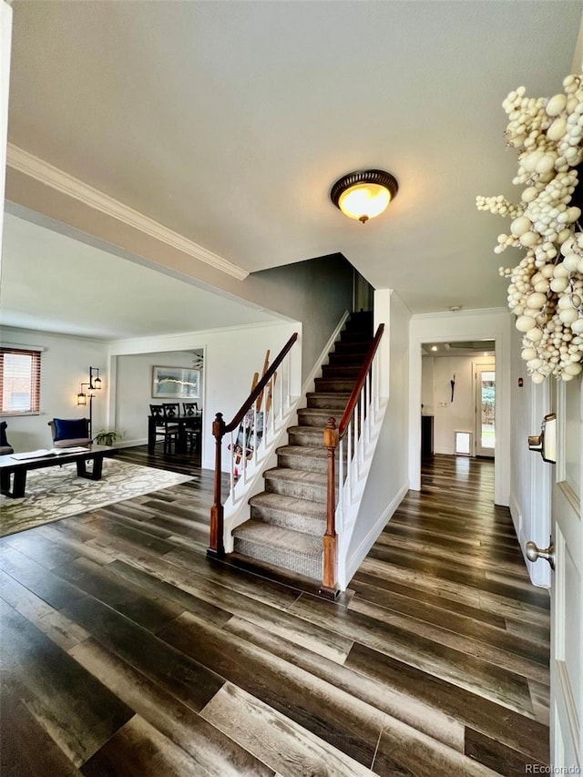 staircase featuring baseboards, ornamental molding, and wood finished floors