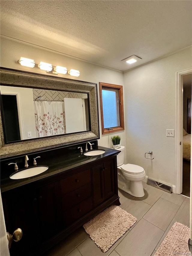 bathroom featuring a sink, double vanity, toilet, and a textured ceiling