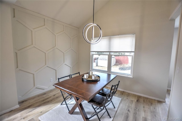 dining space with light hardwood / wood-style floors and high vaulted ceiling