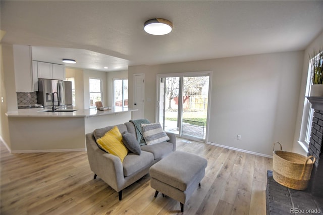 living room with plenty of natural light, sink, a fireplace, and light hardwood / wood-style flooring