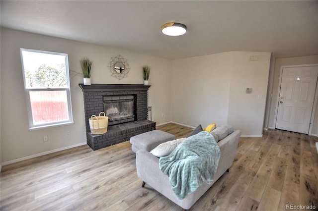 living room with light wood-type flooring and a brick fireplace