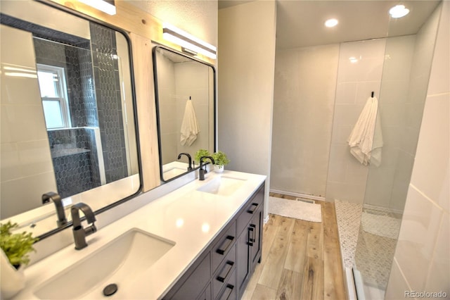 bathroom with hardwood / wood-style floors, vanity, and a tile shower