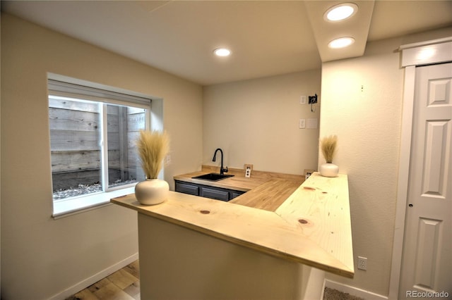 bar with light hardwood / wood-style floors, sink, and wooden counters