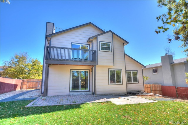 rear view of house featuring a patio, a balcony, and a lawn