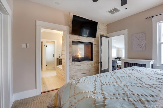 bedroom featuring a fireplace, tile patterned floors, and ceiling fan