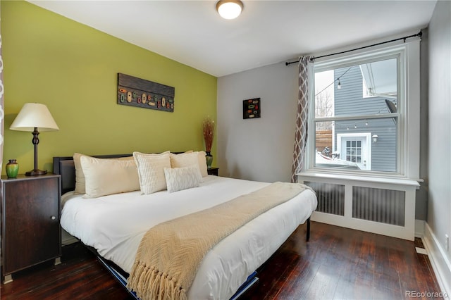 bedroom with dark hardwood / wood-style floors and radiator