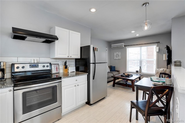 kitchen with stainless steel appliances, wall chimney exhaust hood, white cabinets, an AC wall unit, and dark stone counters