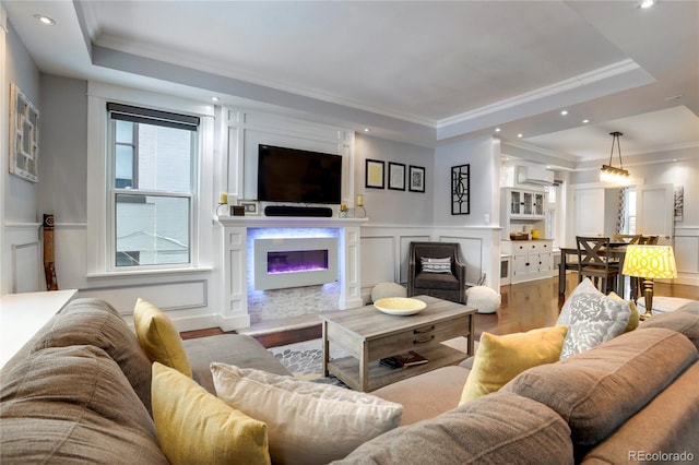 living room with ornamental molding, hardwood / wood-style floors, a wall unit AC, and a tray ceiling