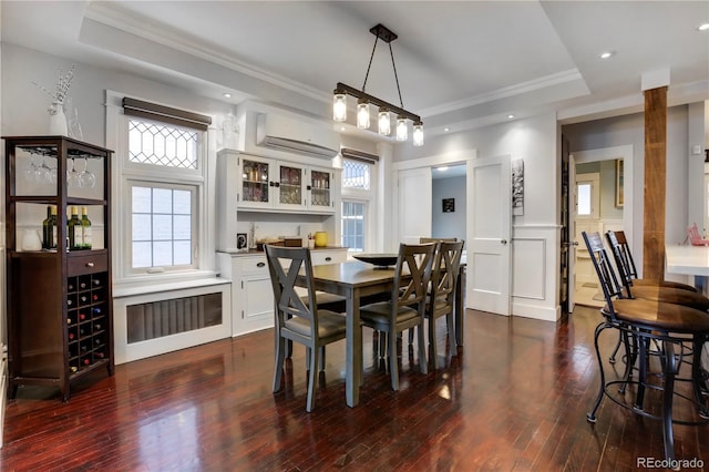 dining room featuring a healthy amount of sunlight, a tray ceiling, and a wall unit AC