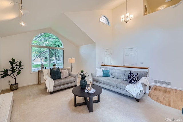 carpeted living room featuring a notable chandelier and high vaulted ceiling