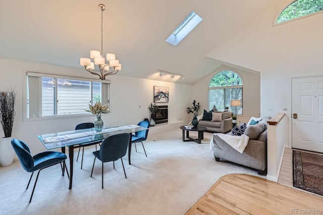 carpeted dining area featuring a notable chandelier, rail lighting, a skylight, and plenty of natural light