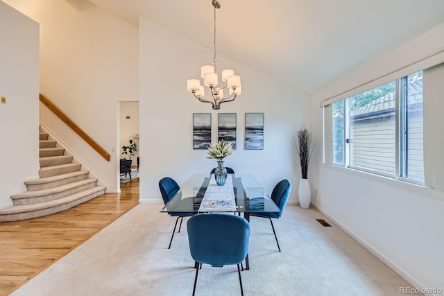 dining space with an inviting chandelier, high vaulted ceiling, and hardwood / wood-style flooring