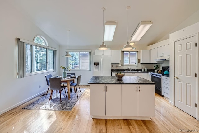 kitchen with white refrigerator with ice dispenser, black electric range oven, white cabinets, and a kitchen island