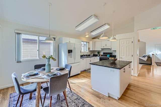 kitchen featuring hanging light fixtures, vaulted ceiling, white cabinetry, light wood-type flooring, and white fridge with ice dispenser