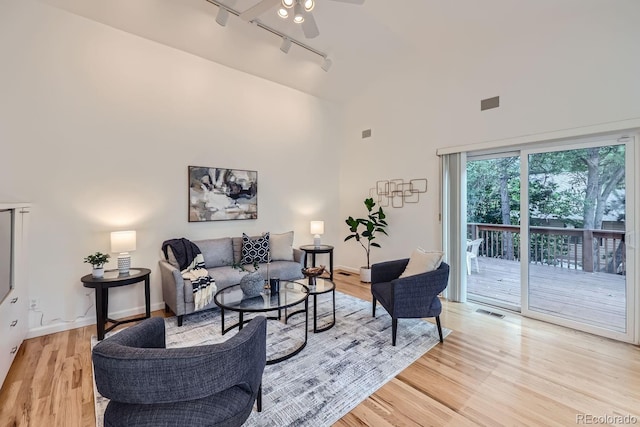 living room featuring ceiling fan, light wood-type flooring, a high ceiling, and rail lighting