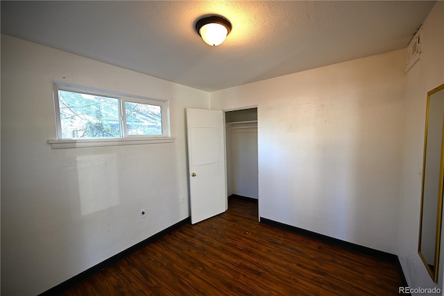 unfurnished bedroom with dark hardwood / wood-style floors and a closet