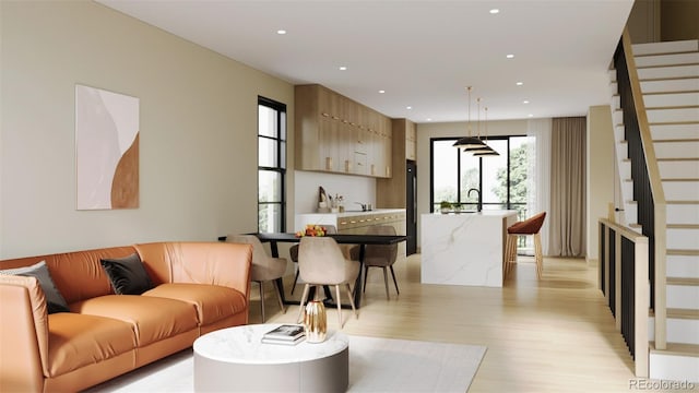 living room featuring a healthy amount of sunlight, sink, and light hardwood / wood-style flooring