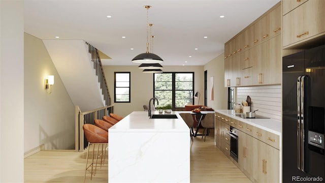 kitchen with sink, a kitchen island with sink, black appliances, a kitchen bar, and decorative light fixtures