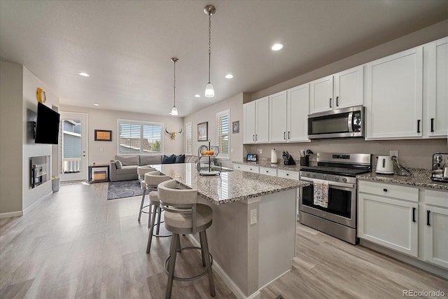 8908 Birch Run Ln, Parker, CO 80134 - kitchen with stainless steel appliances, light wood-style floors, open floor plan, light stone counters, and white cabinets