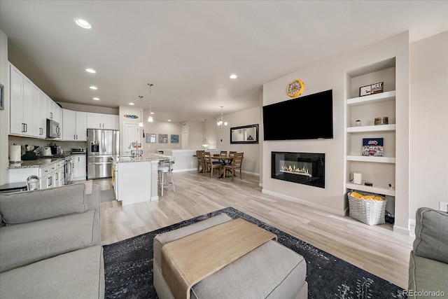 8908 Birch Run Ln, Parker, CO 80134 - living room featuring light wood-style flooring, built in shelves, recessed lighting, and a glass covered fireplace