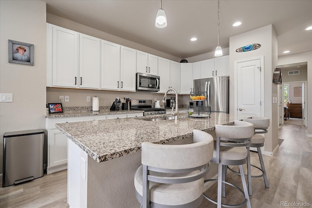 8908 Birch Run Ln, Parker, CO 80134 - kitchen with appliances with stainless steel finishes, light wood-style floors, a kitchen bar, light stone countertops, and recessed lighting