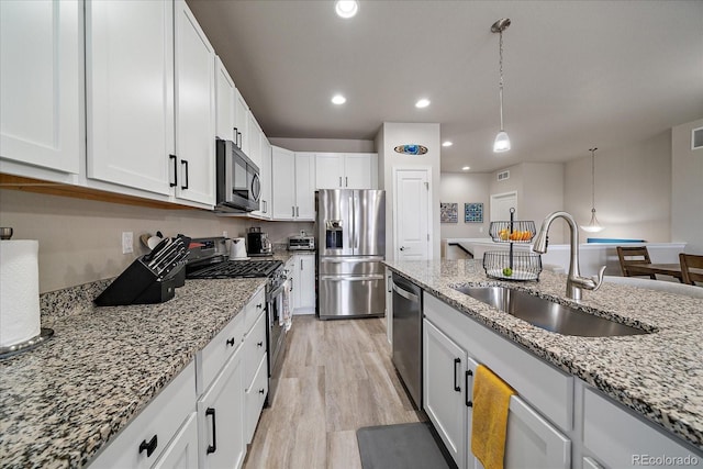 8908 Birch Run Ln, Parker, CO 80134 - kitchen featuring appliances with stainless steel finishes, light stone countertops, white cabinetry, light wood-style floors, and decorative light fixtures