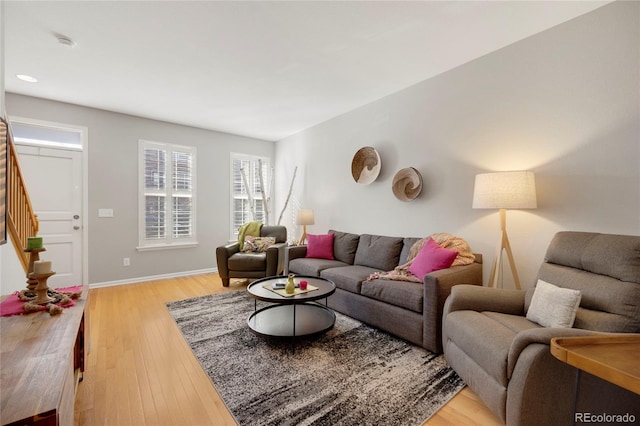 living room with stairs, light wood-type flooring, and baseboards