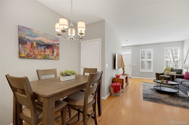 dining space featuring a chandelier, light wood finished floors, and baseboards